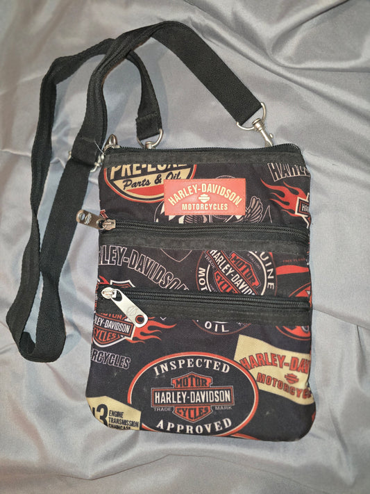 Sling this pre-owned Harley-Davidson® Women's X-Body Oil Print Crossbody Bag over your shoulder and show off your edgy side. Made with zipper pull logos and quality craftsmanship, this bag is both stylish and functional. Great for any occasion, this bag is sure to make a statement! Noted the strap on the back is coming loose, but feels secure. 