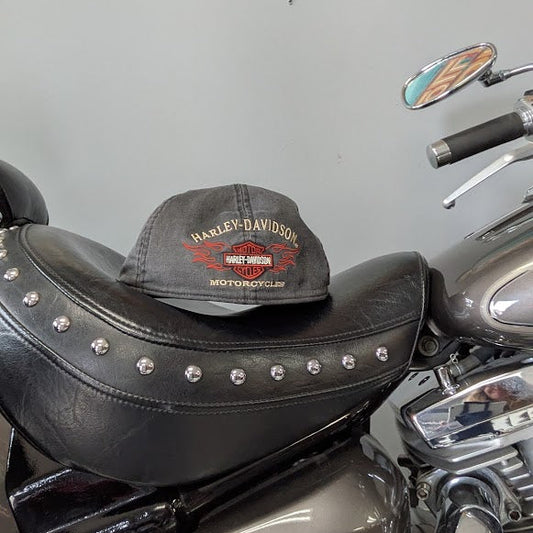 Harley Davidson cap on a motorcycle seat with a colorful background
