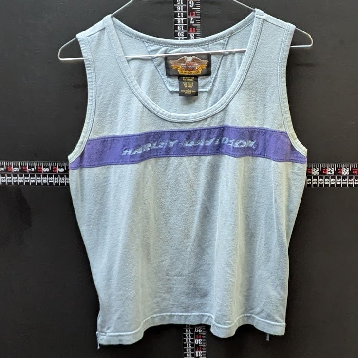 Light blue tank top with purple stripe on a hanger against a dark background