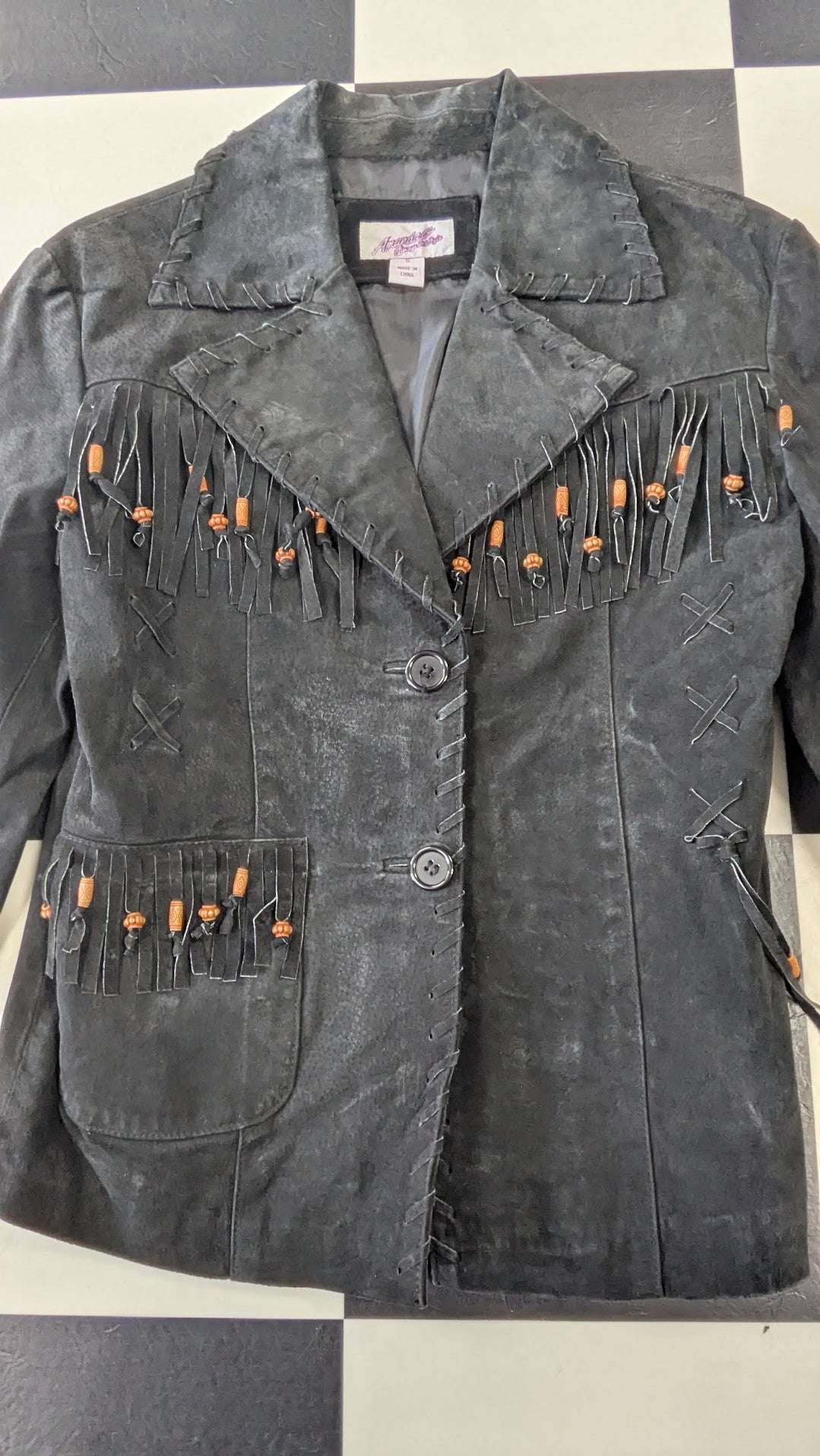 Black jacket with fringe details on a checkered background