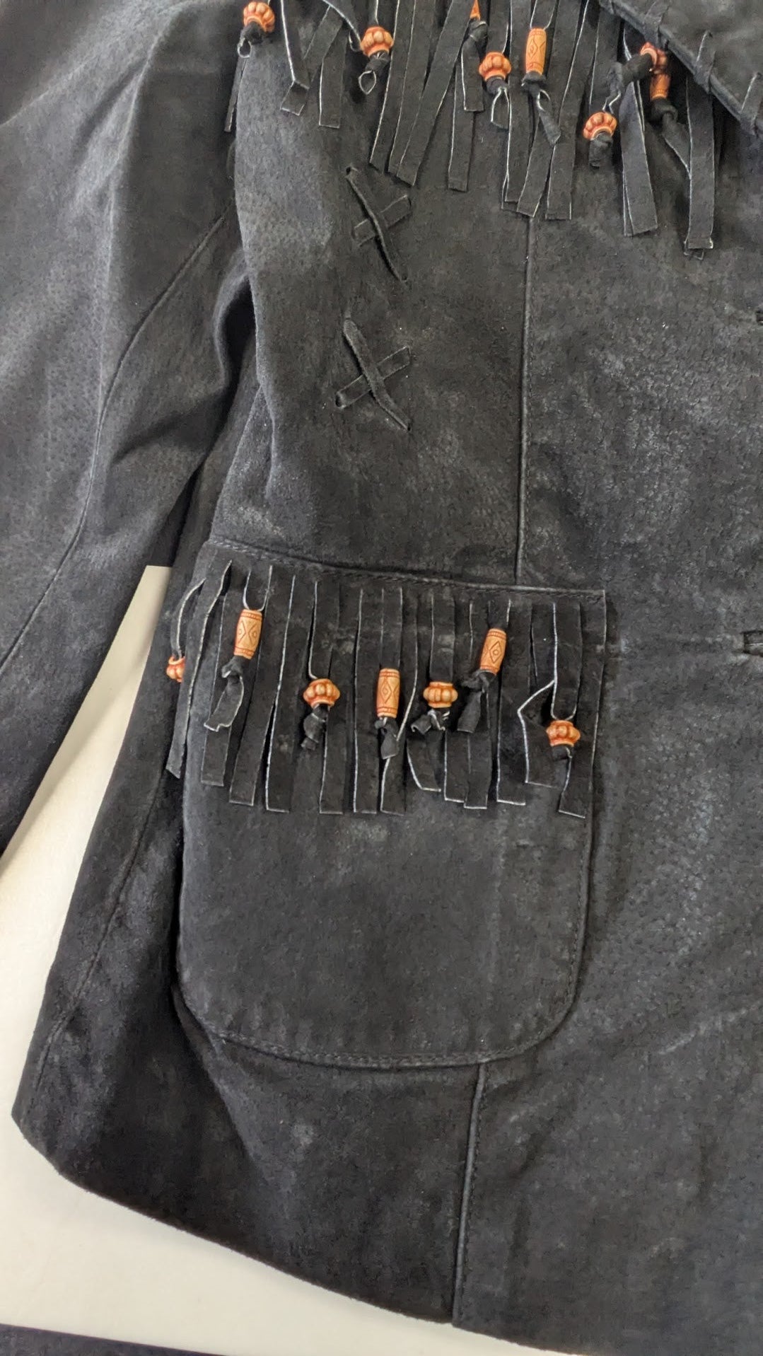 Leather suede jacket with orange buttons and decorative elements on a light background