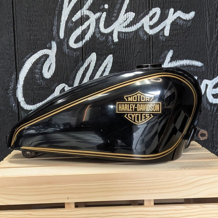 Harley-Davidson motorcycle fuel tank on a wooden crate with a black background featuring 'Biker Collective' text.