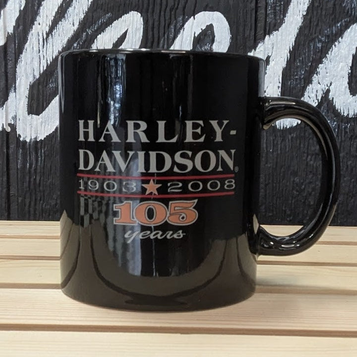 Black Harley-Davidson mug on a wooden surface with a dark background featuring white text.