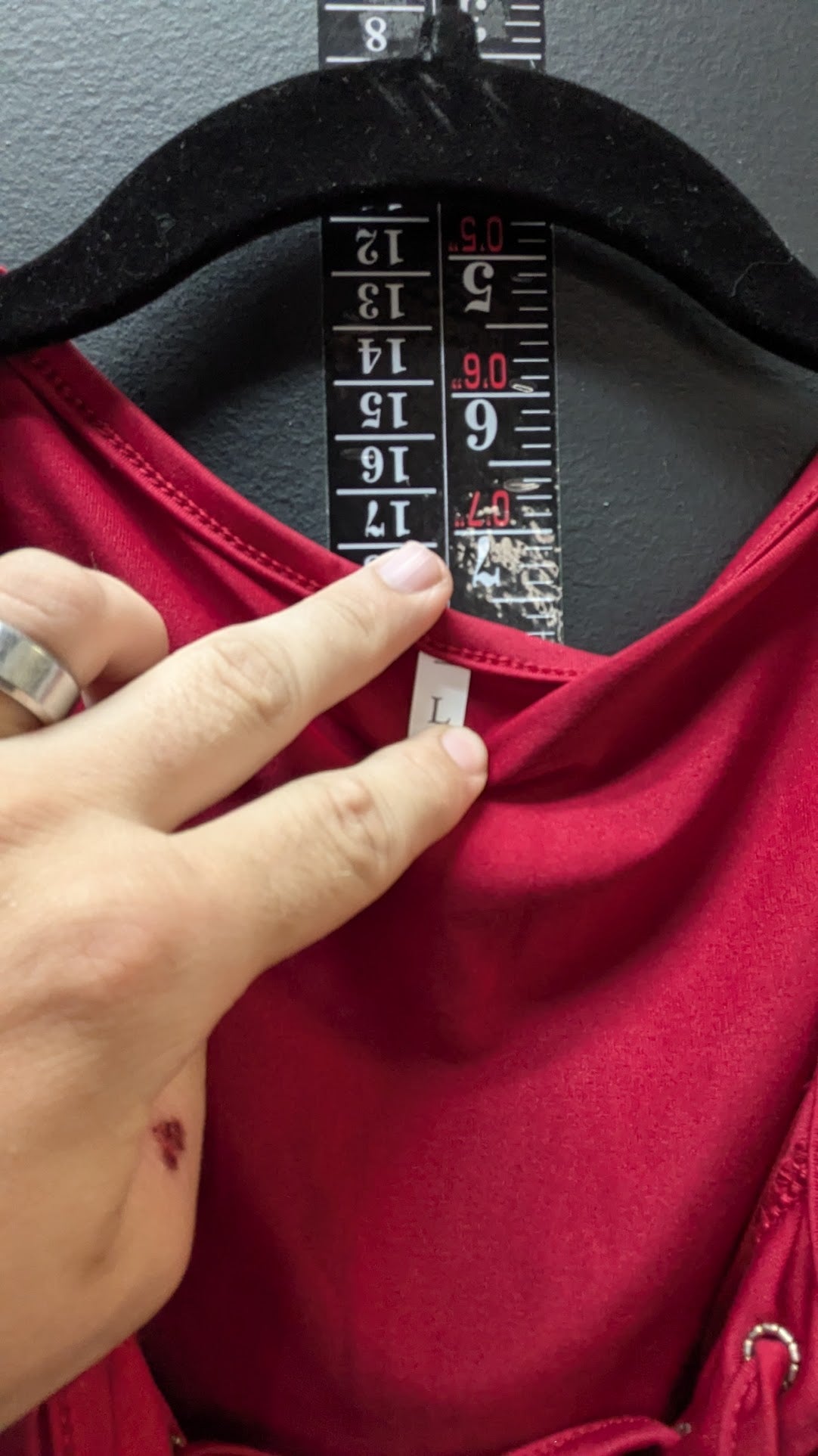 Red shirt with a hand holding a measuring tape against it