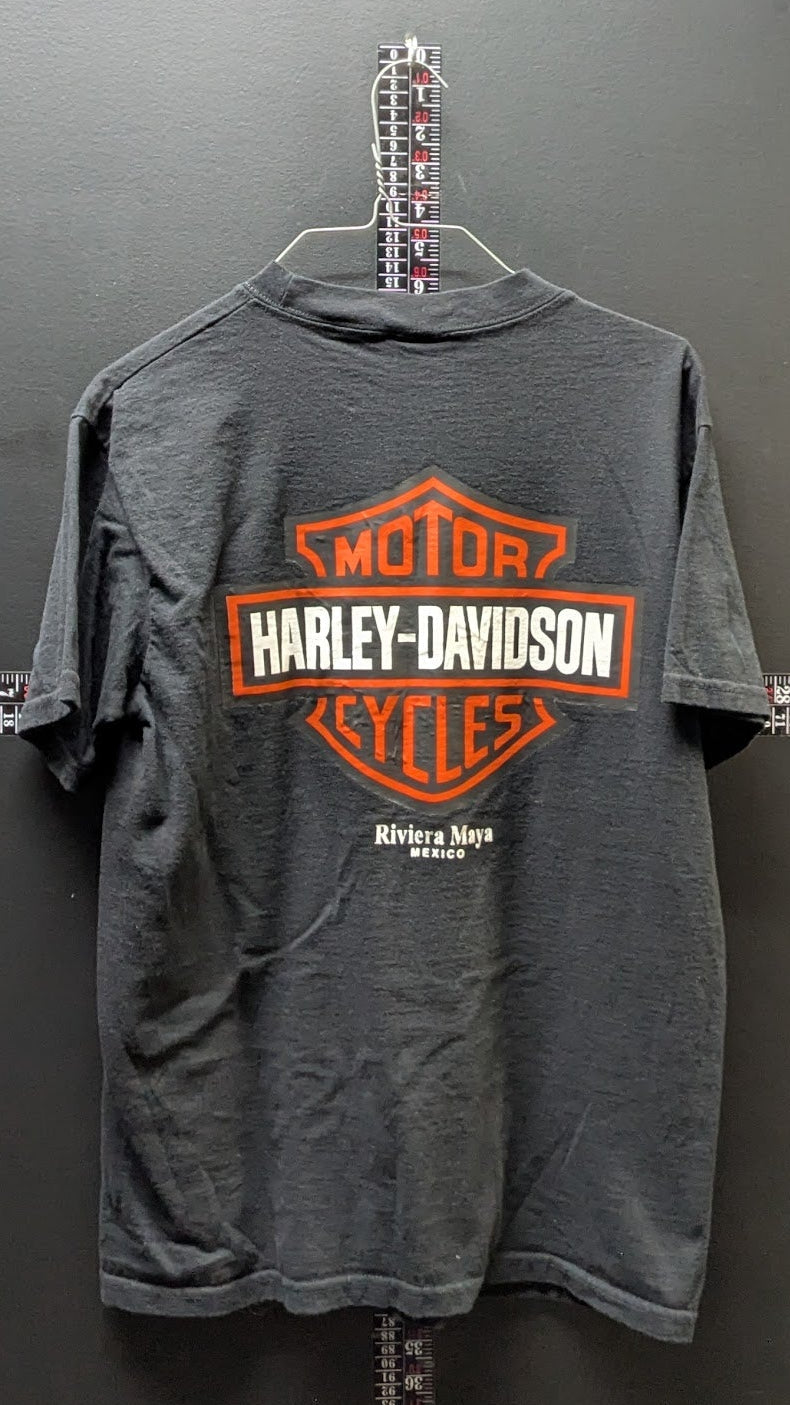 A dark gray short-sleeve t-shirt hanging on a wire hanger against a dark gray wall, featuring a large orange and white Harley-Davidson logo graphic on the back.