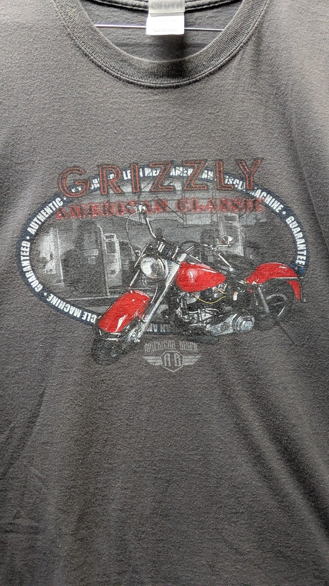 A dark gray heather graphic t-shirt featuring a red and black motorcycle print with the text 'GRIZZLY AMERICAN CLASSIC' and a Harley-Davidson logo.