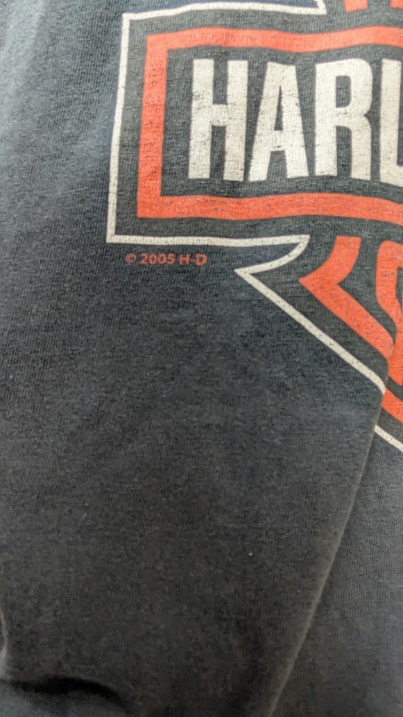 Close-up of a dark gray graphic t-shirt featuring the Harley-Davidson logo in orange and white, with a copyright notice for 2005 H-D.