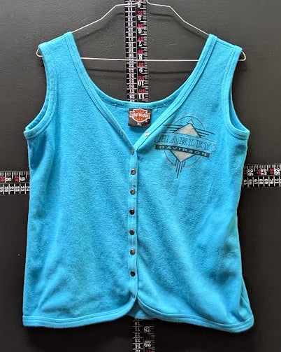 A turquoise blue sleeveless vest with a button-up front and a distressed graphic on the left chest, hanging on a wire hanger against a dark gray wall.