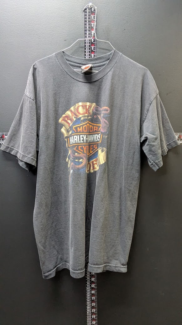 A faded gray short-sleeve t-shirt hanging on a metal hanger against a dark gray wall, featuring a vintage-style Harley-Davidson graphic on the front.