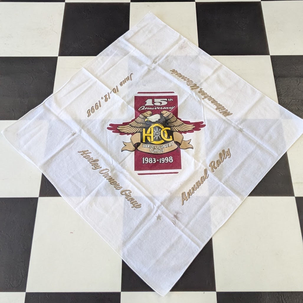 A white square bandana featuring a vintage hockey design with a central red and gold 'Hockey Club' logo and gold script text, laid flat on a black and white checkered floor.